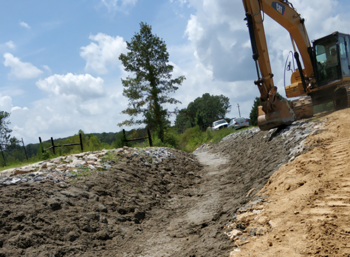 A yellow excavator is digging a hole in the dirt.
