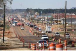 A busy street with a lot of traffic and cones on the side of it.