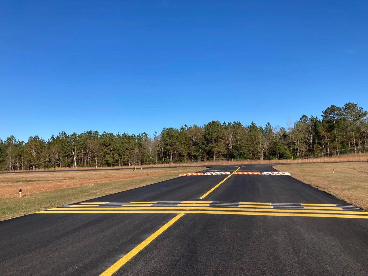 A runway with trees in the background and a blue sky