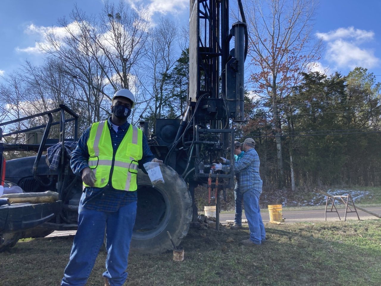 A man in a yellow vest is standing in front of a machine.
