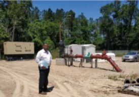 A man in a white shirt is standing in a dirt field