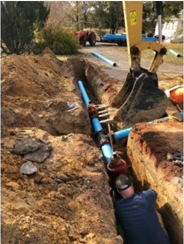 A man is working on a pipe in the dirt