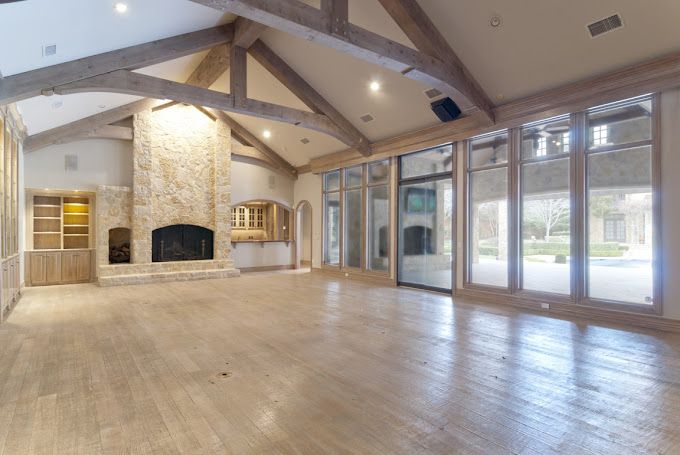 A large empty room with a fireplace and lots of windows