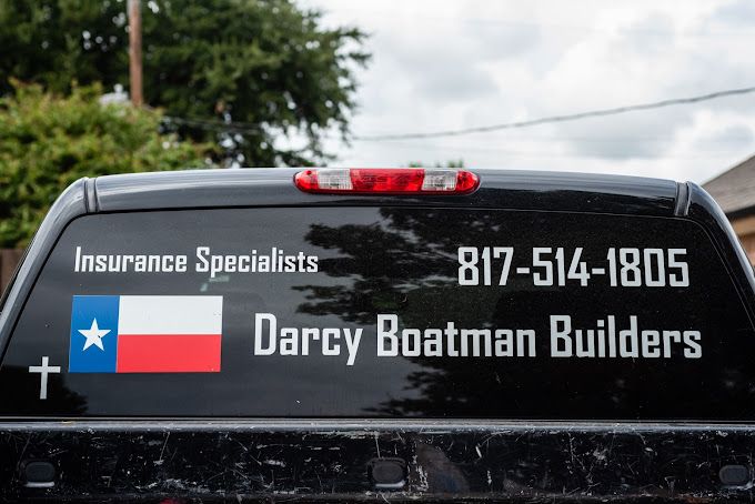 A black truck with a sticker on the back window that says darcy boatman builders
