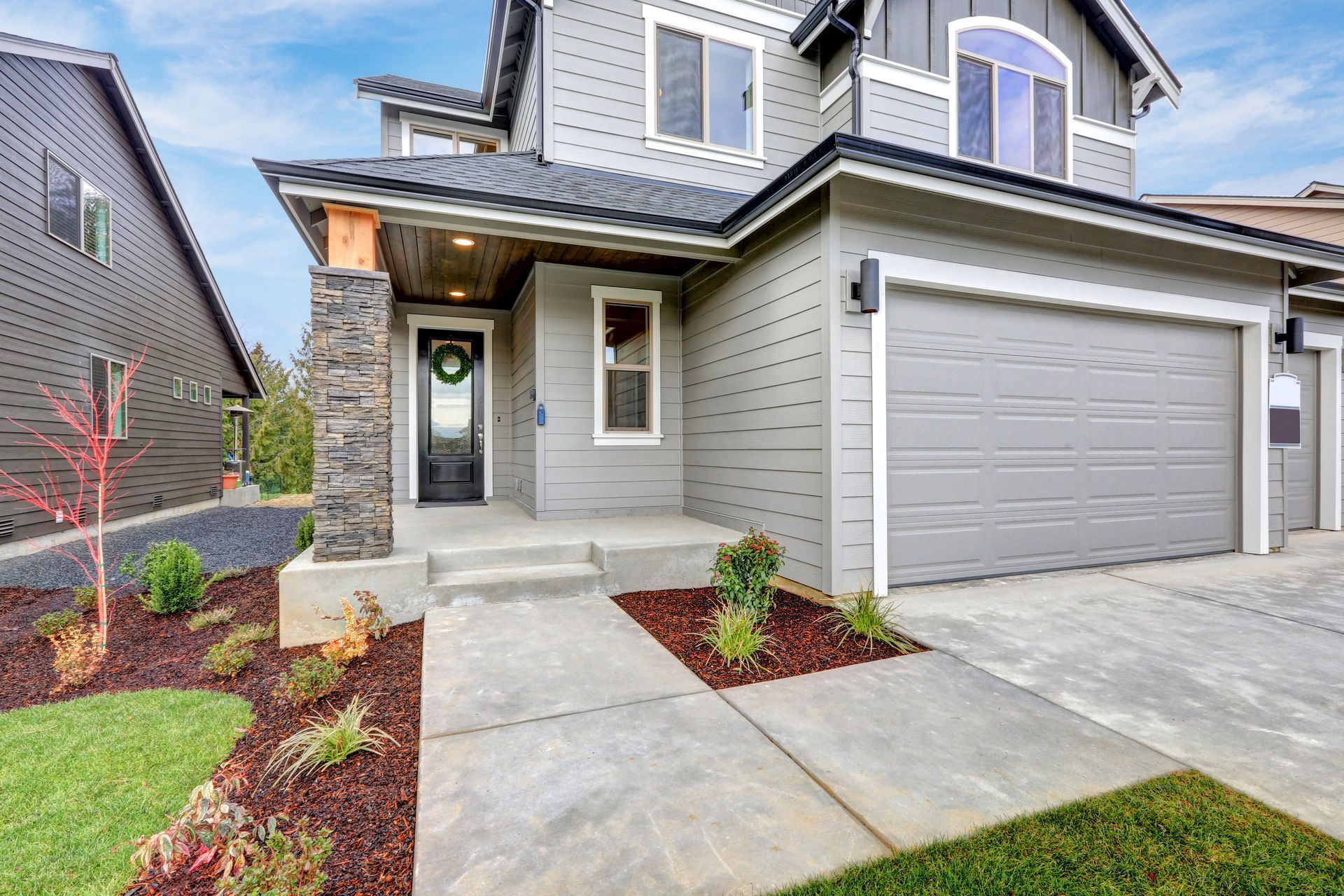 A large gray house with a concrete walkway leading to the front door.