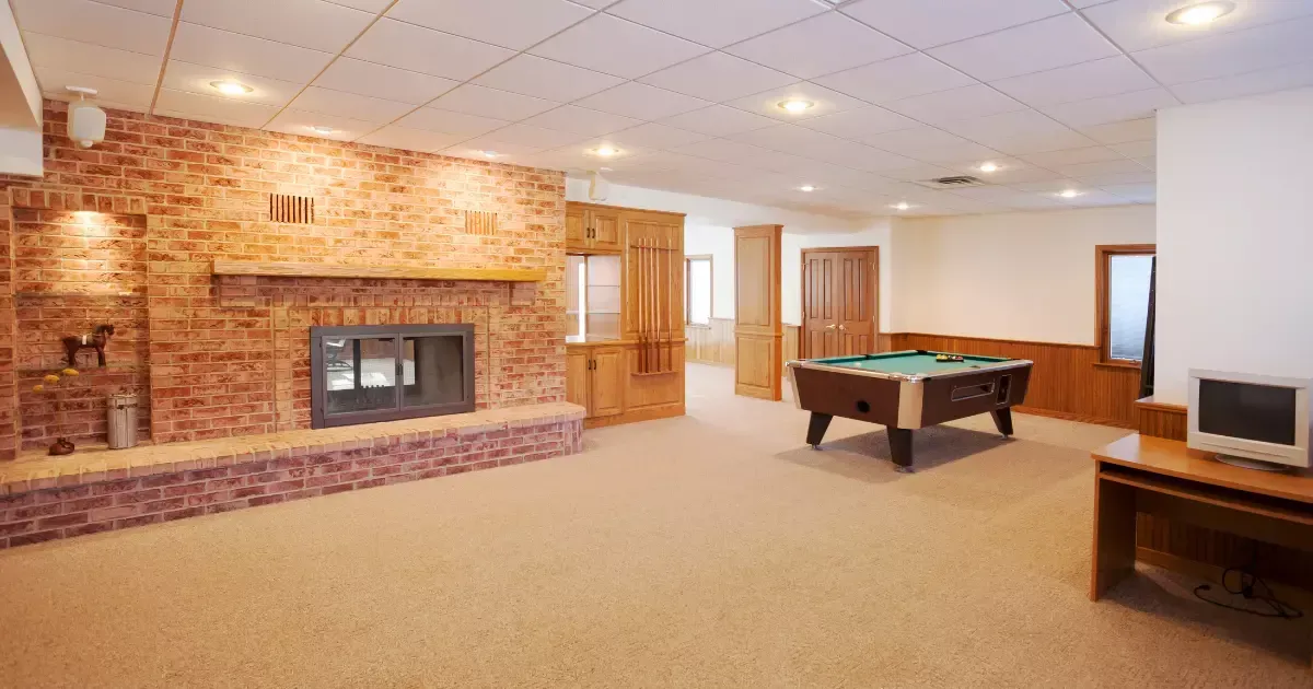 Brick fireplace and pool table in a basement game room setup