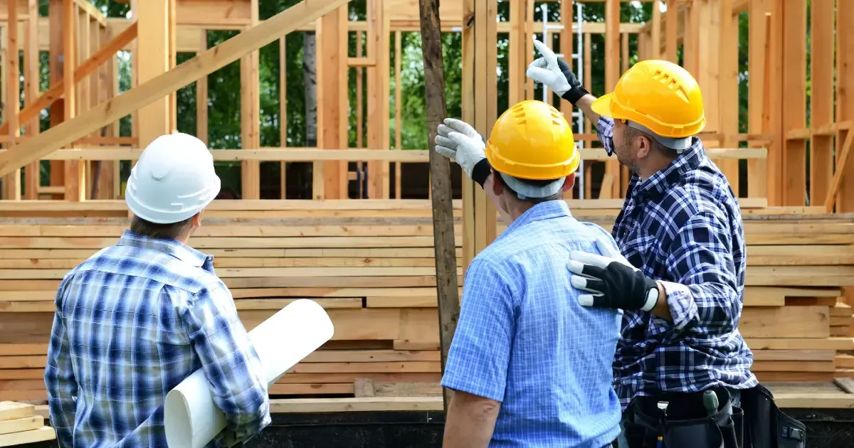 A group of men wearing hard hats and gloves assessing a house construction