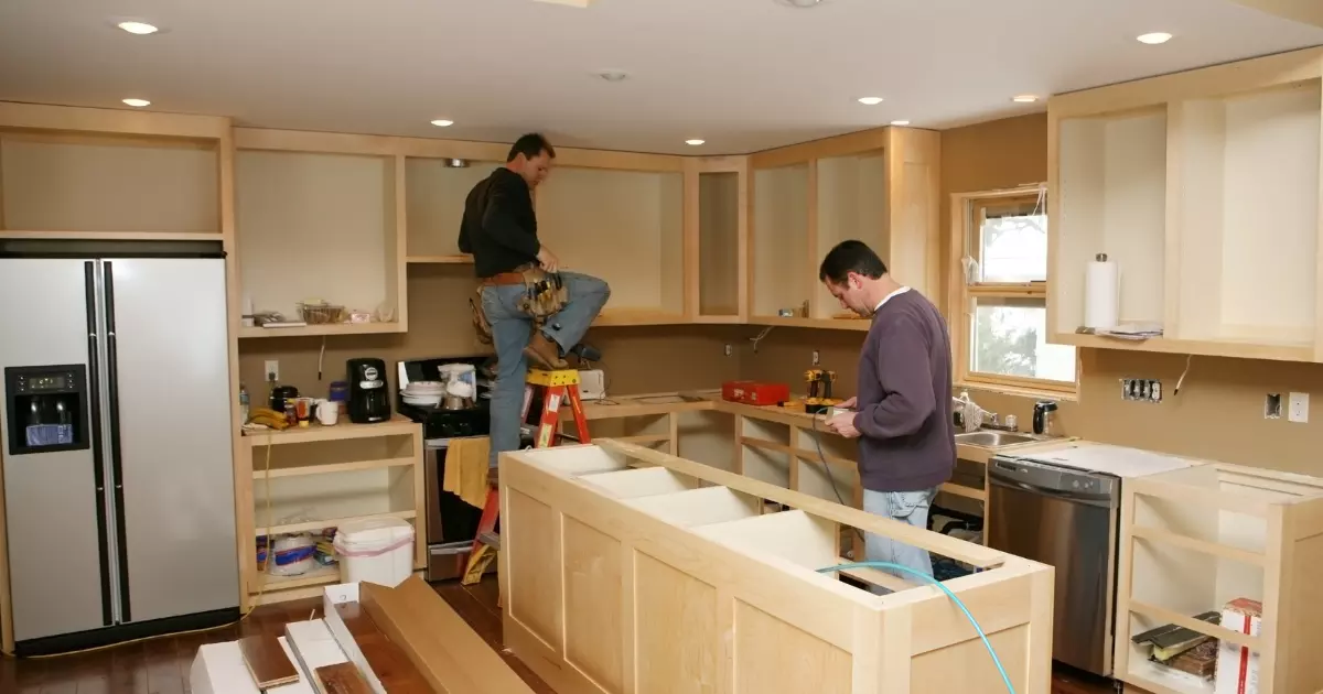 Men installing kitchen cabinets during a renovation project