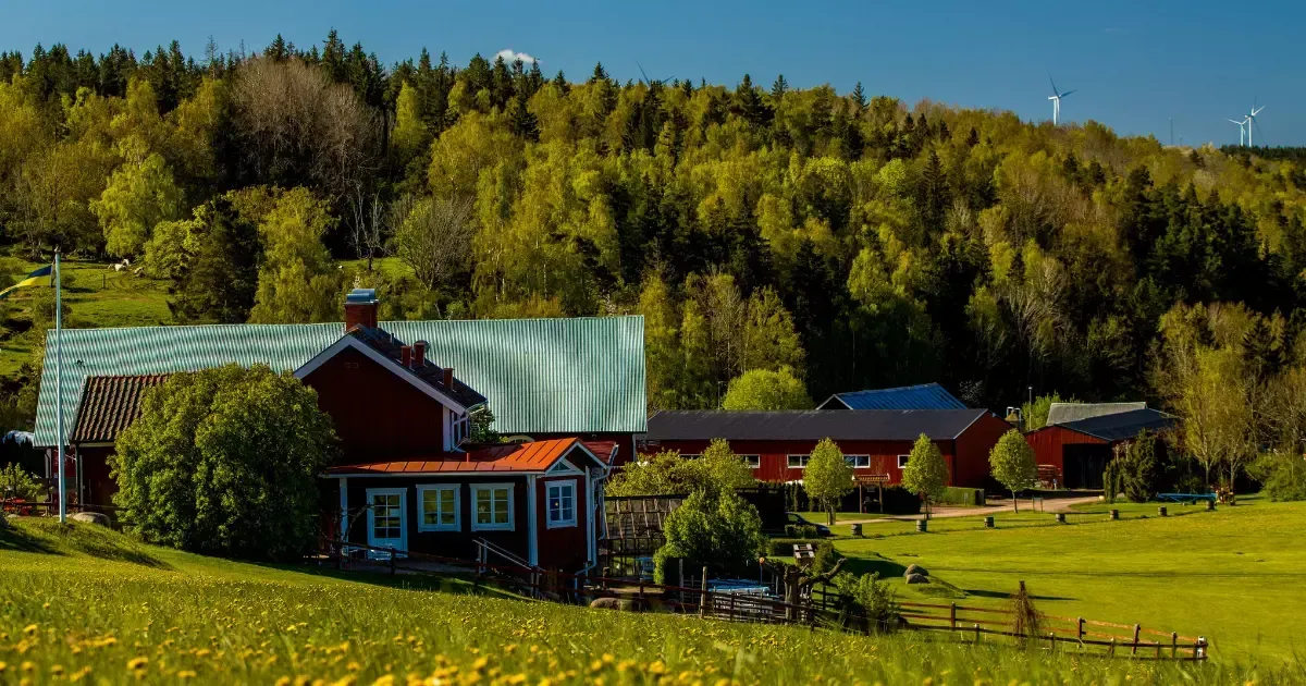 Rustic red farmhouse surrounded by trees and fields, showcasing cozy modern farmhouse home designs
