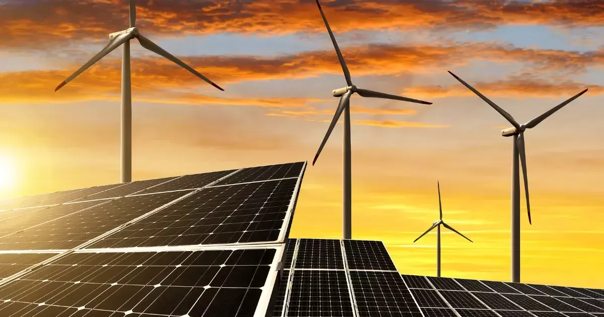 Solar panel and wind turbines generating renewable energy at sunset