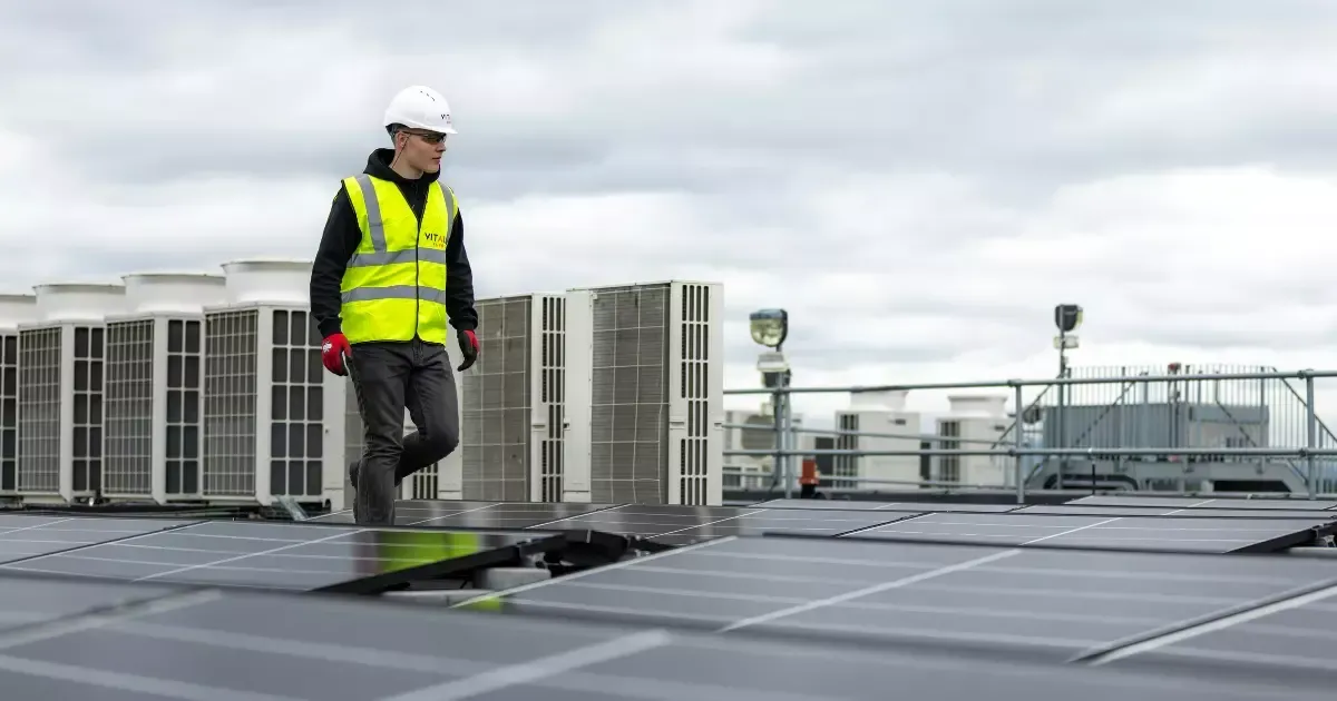 Technician inspecting commercial solar panels installed on a flat rooftop to ensure optimal performance.
