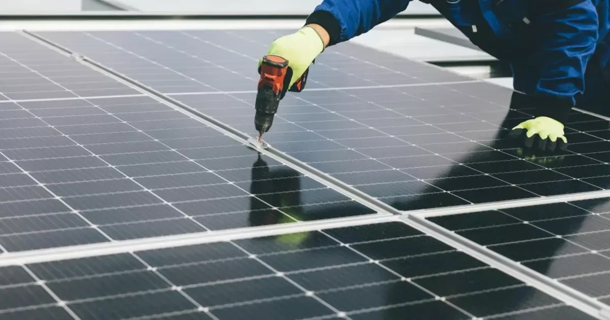 Technician using drill for solar panel maintenance