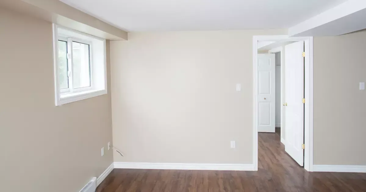 An empty room with hardwood floors and a window.