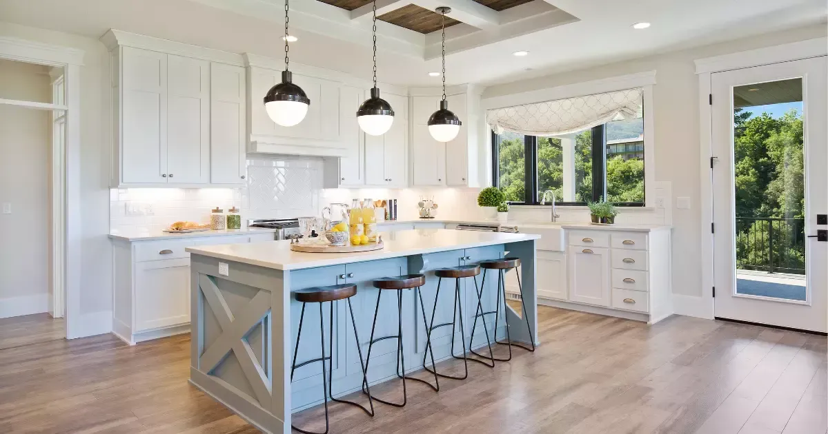 White kitchen with blue island and pendant lights, inspired by modern farmhouse home designs.
