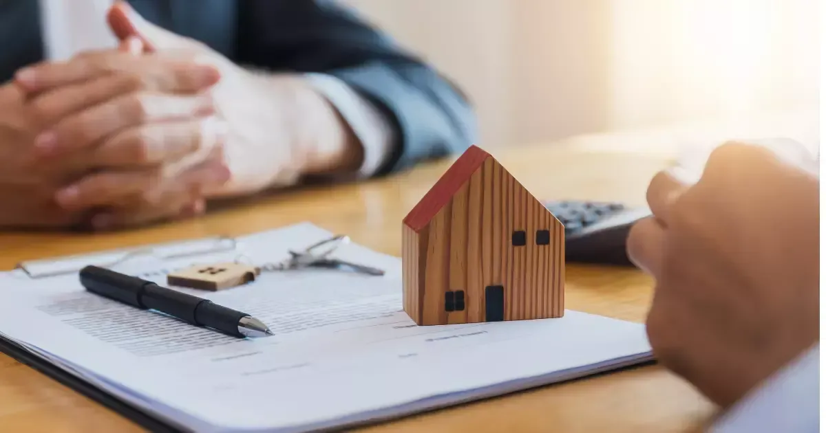 Wooden house model, keys, and contract paperwork symbolizing financing