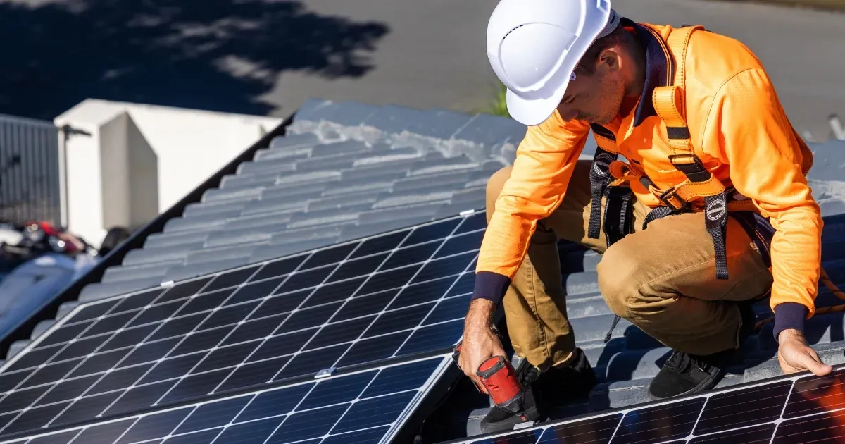 Worker securing roof panels to extend solar panel lifespan