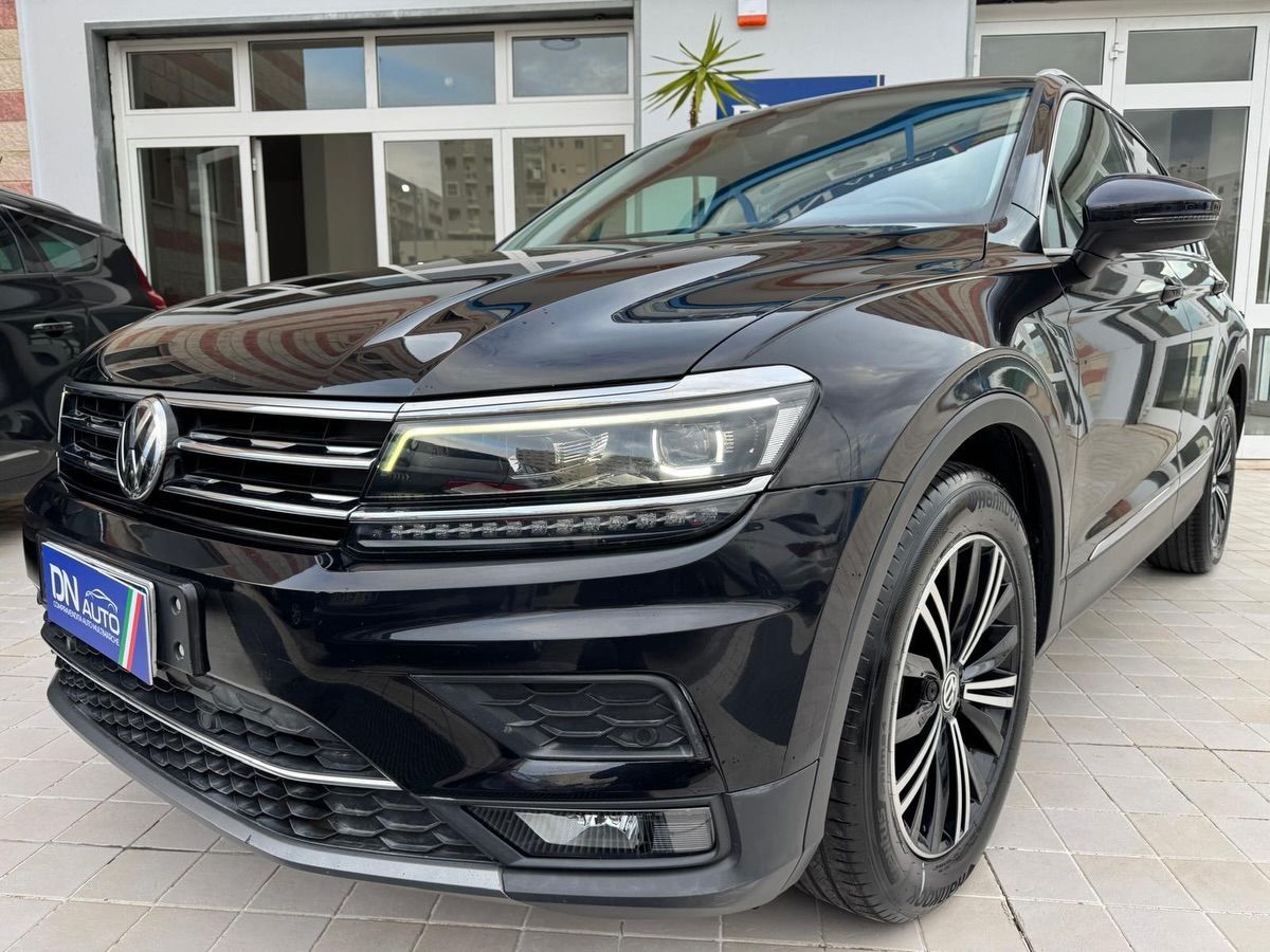 Un SUV Volkswagen Tiguan nero lucido parcheggiato davanti a un edificio con grandi vetrate.
