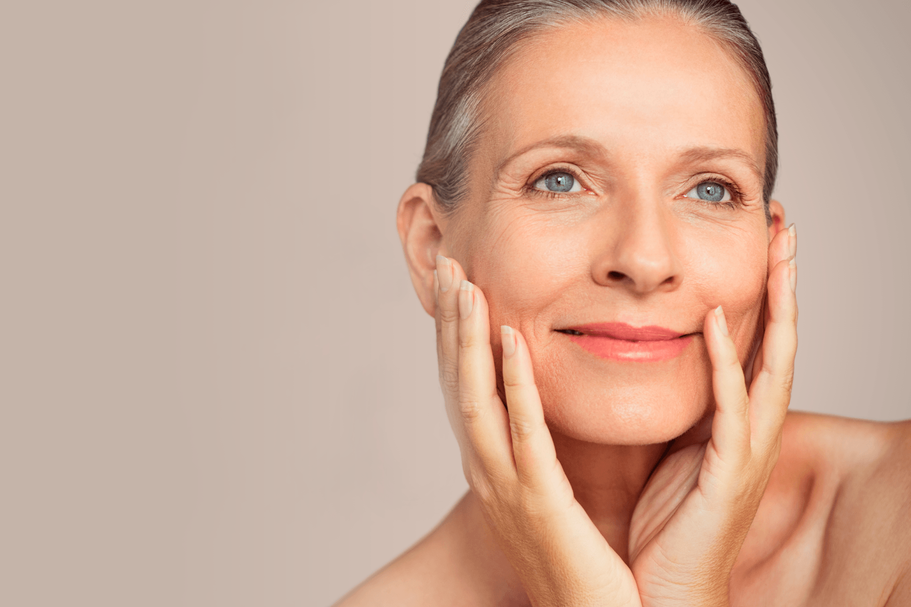 A woman is touching her face with her hands and smiling.