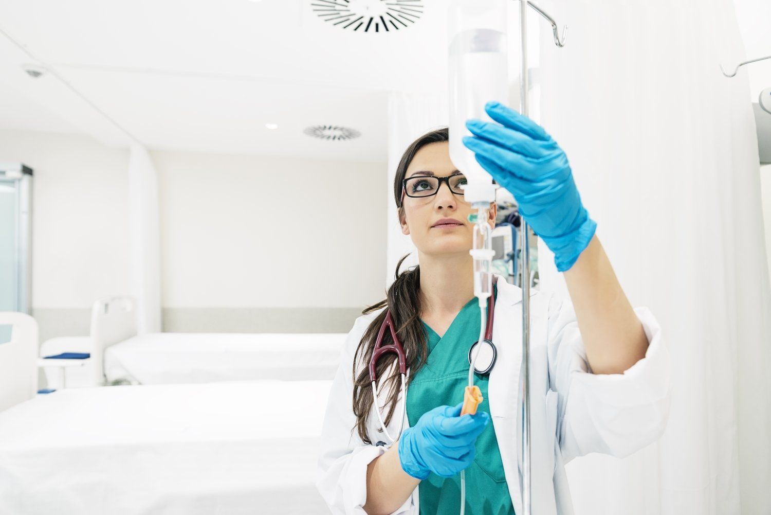 A female doctor is preparing an iv in a hospital room.