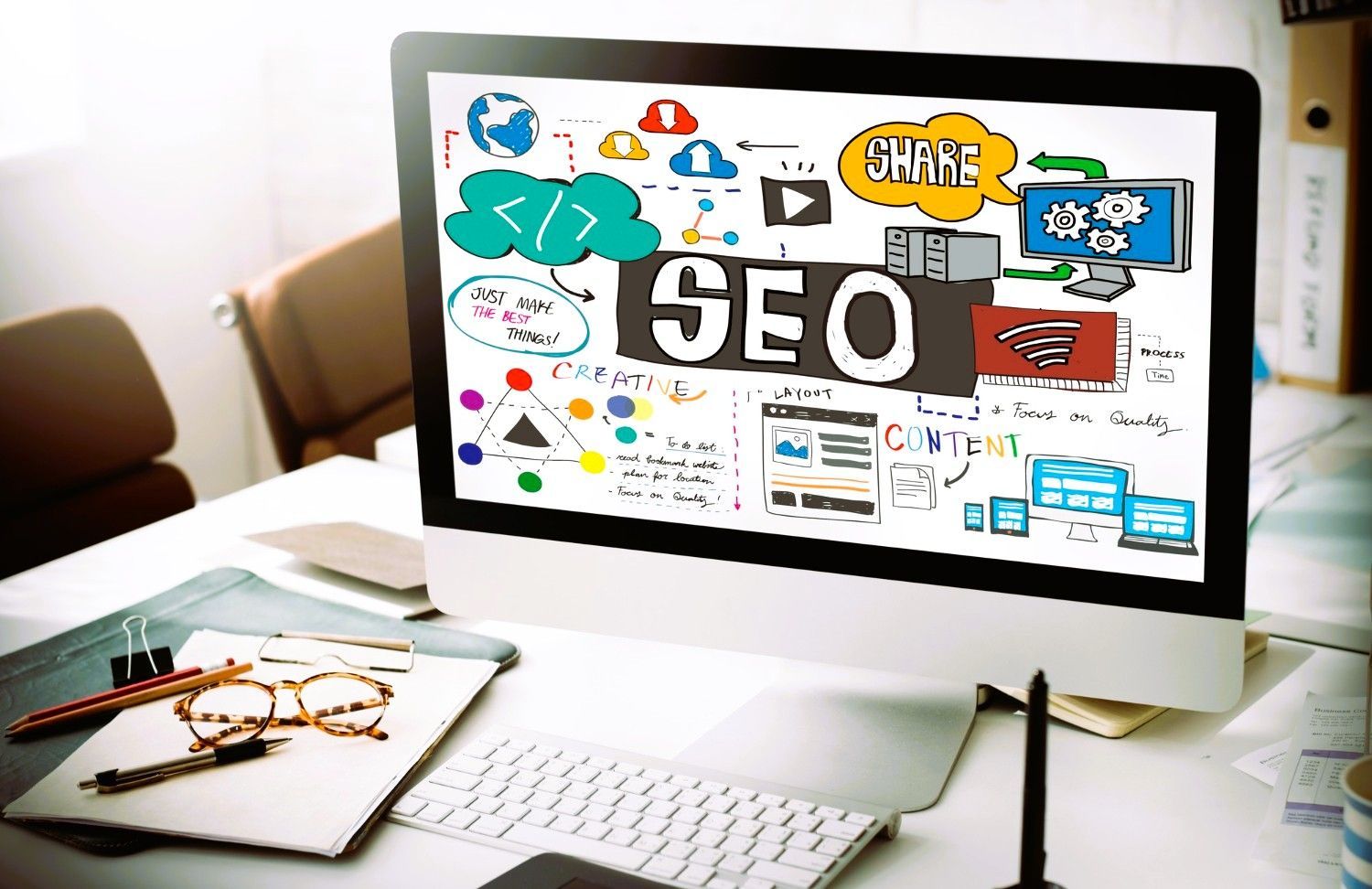 Monitor showing colorful SEO and content doodles on desk.