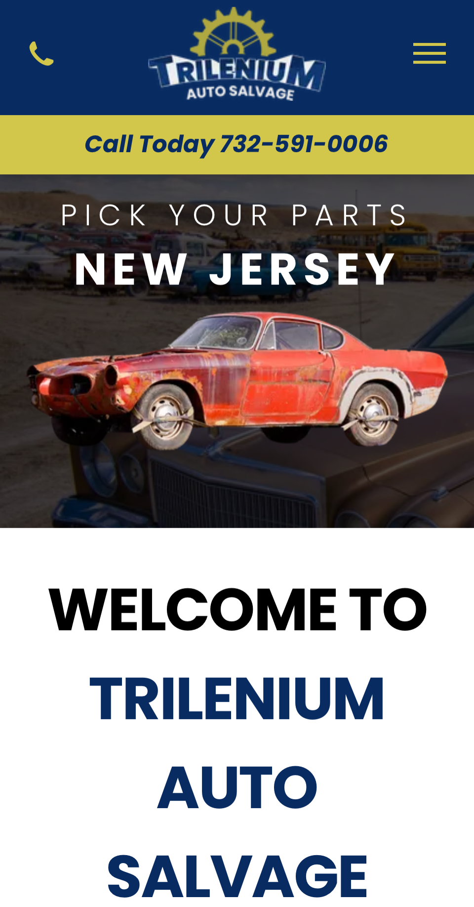 A red car is sitting on top of a truck in a parking lot.