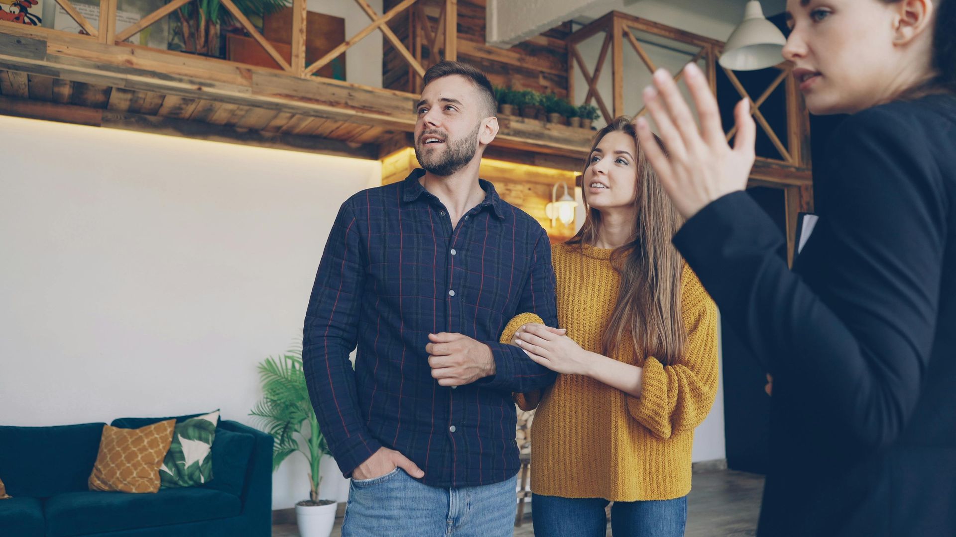 Three coworkers stand in a modern office, one clapping while the others watch attentively.