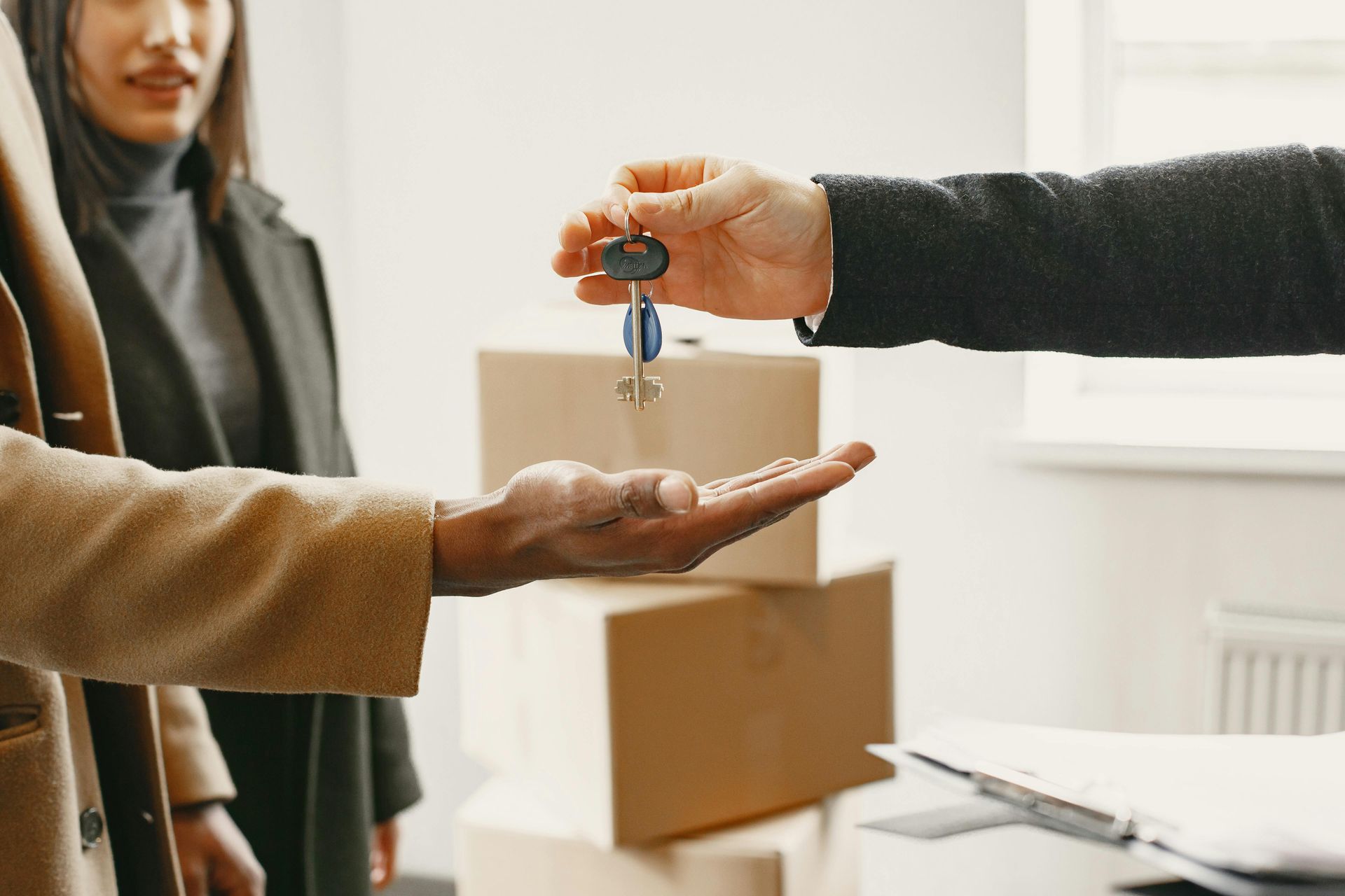 Handing over house keys during a move, with cardboard boxes in the background