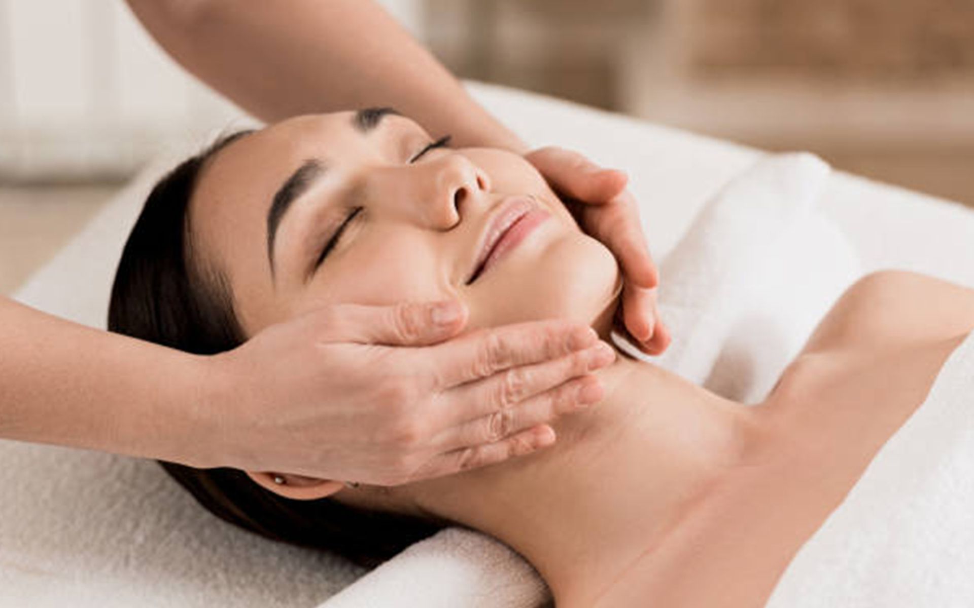 A woman is getting a facial massage at a spa.