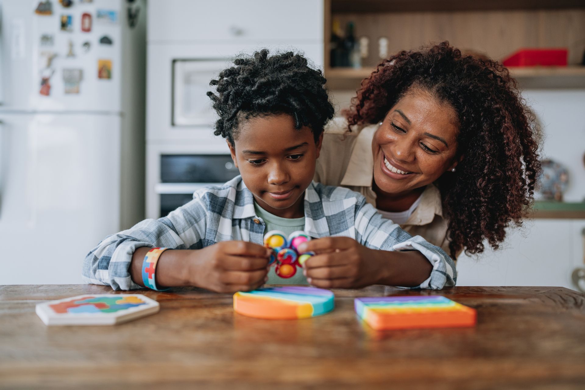 A mother and son are playing with a fidget toy at a table.