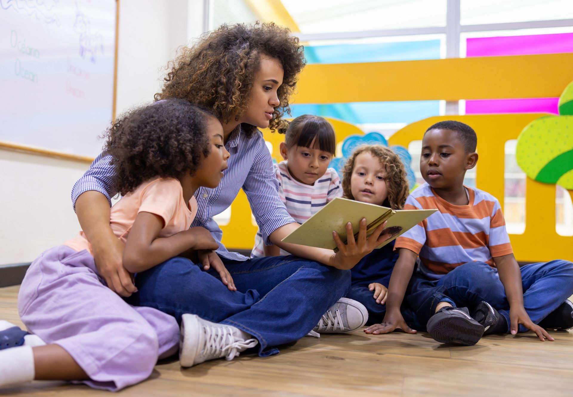 A teacher is reading a book to a group of children.