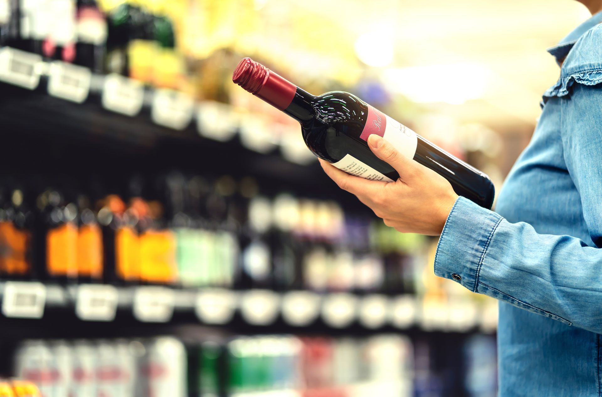 Customer browsing a bottle of wine at a liquor shop.