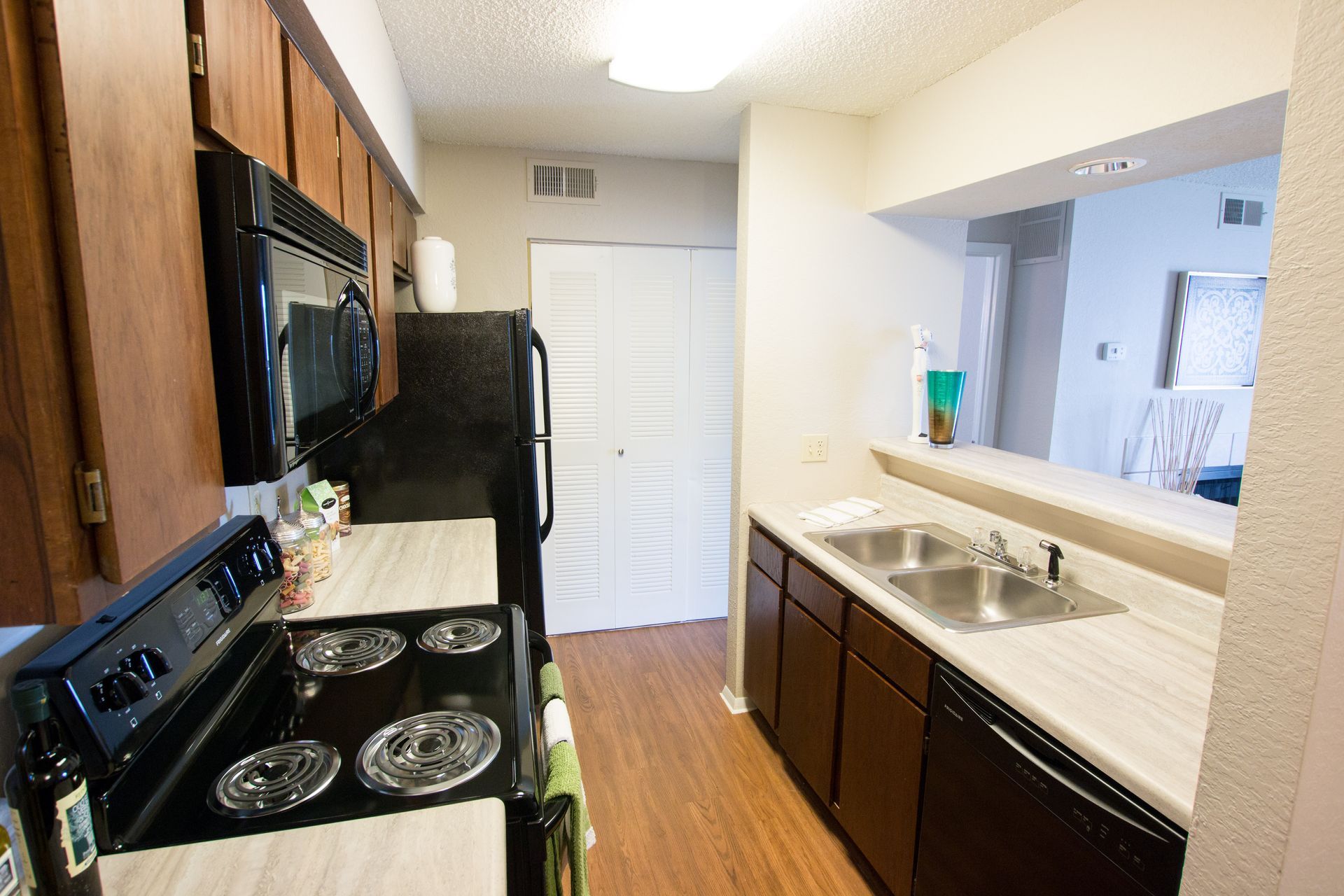 A kitchen with a stove , sink , refrigerator and microwave.