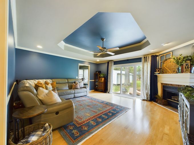 A living room with a couch , rug , fireplace and ceiling fan.