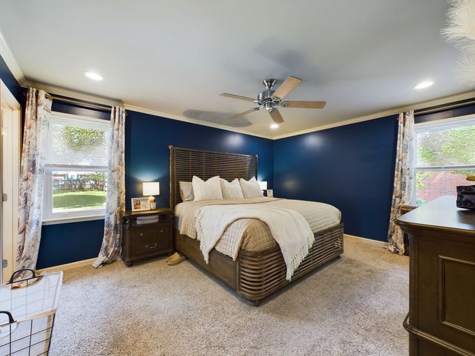 A bedroom with a bed , dresser , nightstand and ceiling fan.