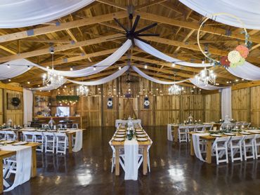 A large room with tables and chairs set up for a wedding reception.