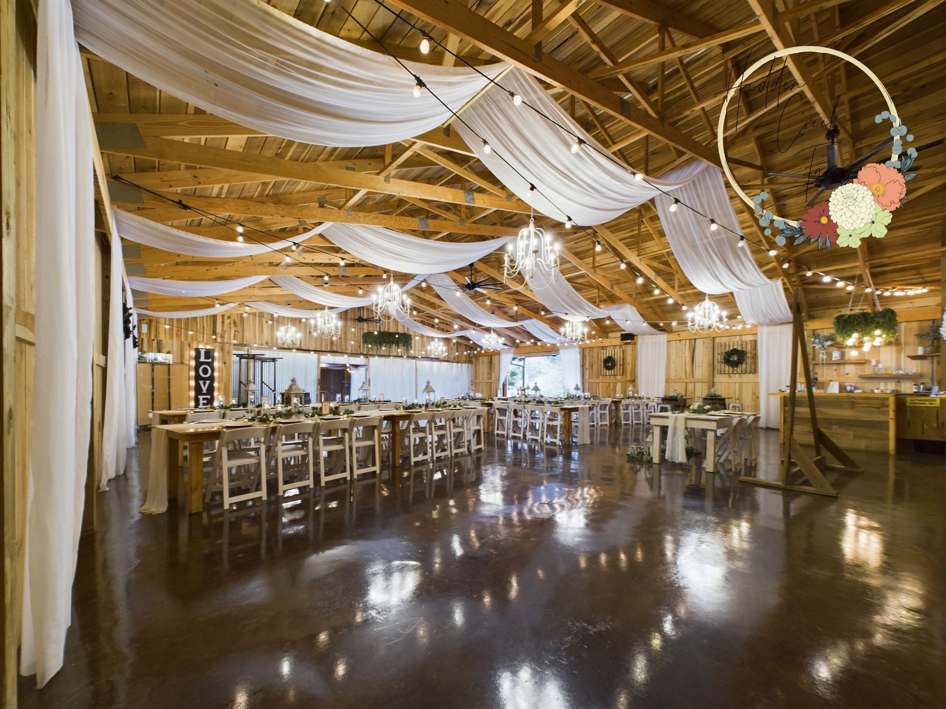 A large room with tables and chairs in it is decorated for a wedding reception.