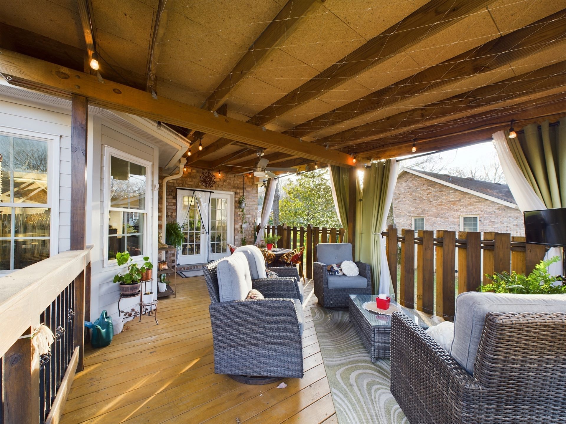 A large deck with wicker furniture and a wooden fence.