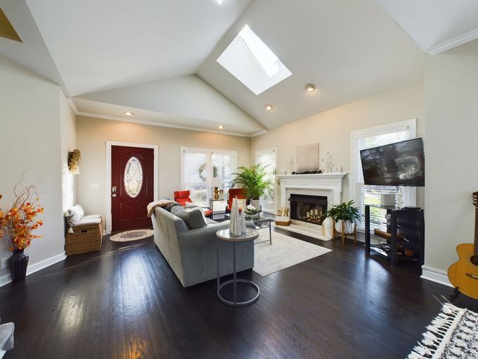 A living room with a couch , fireplace , television and skylight.