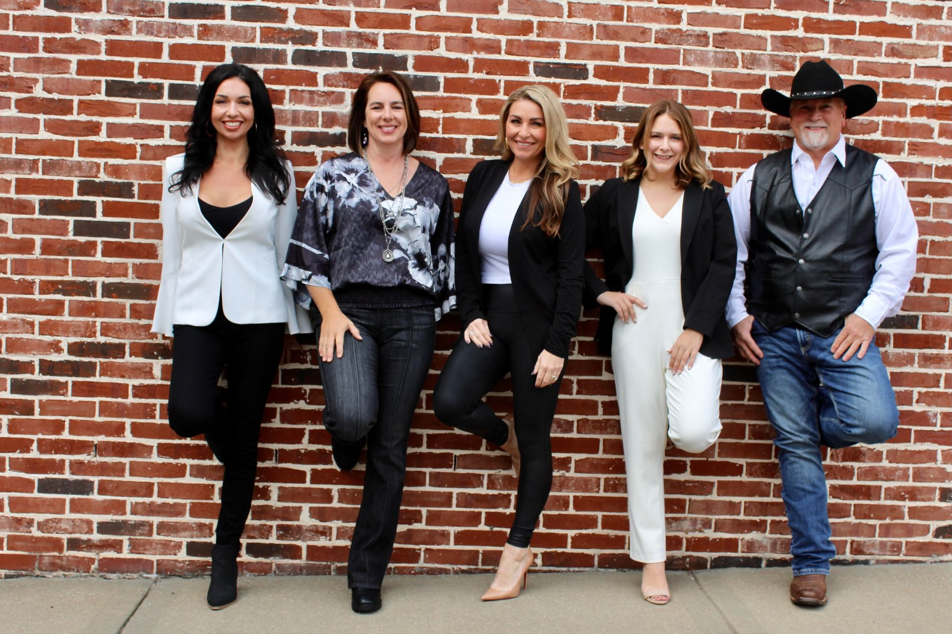 A group of people are standing in front of a brick wall.