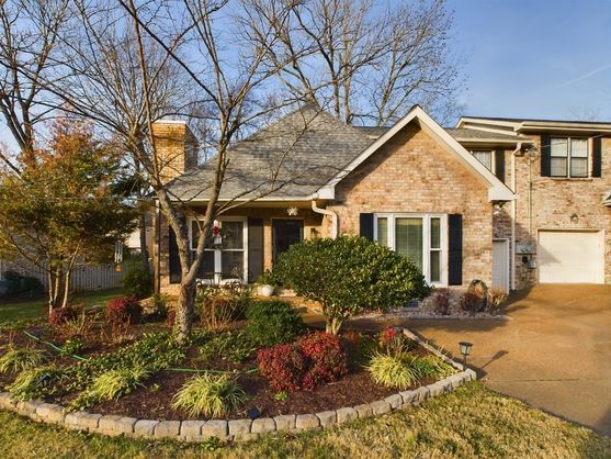 A brick house with a white garage and a lush green yard