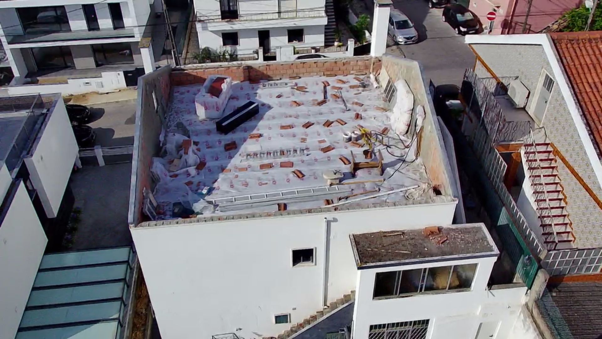 Vista aérea de um edifício em reforma, com o telhado parcialmente removido e entulho espalhado por cima.