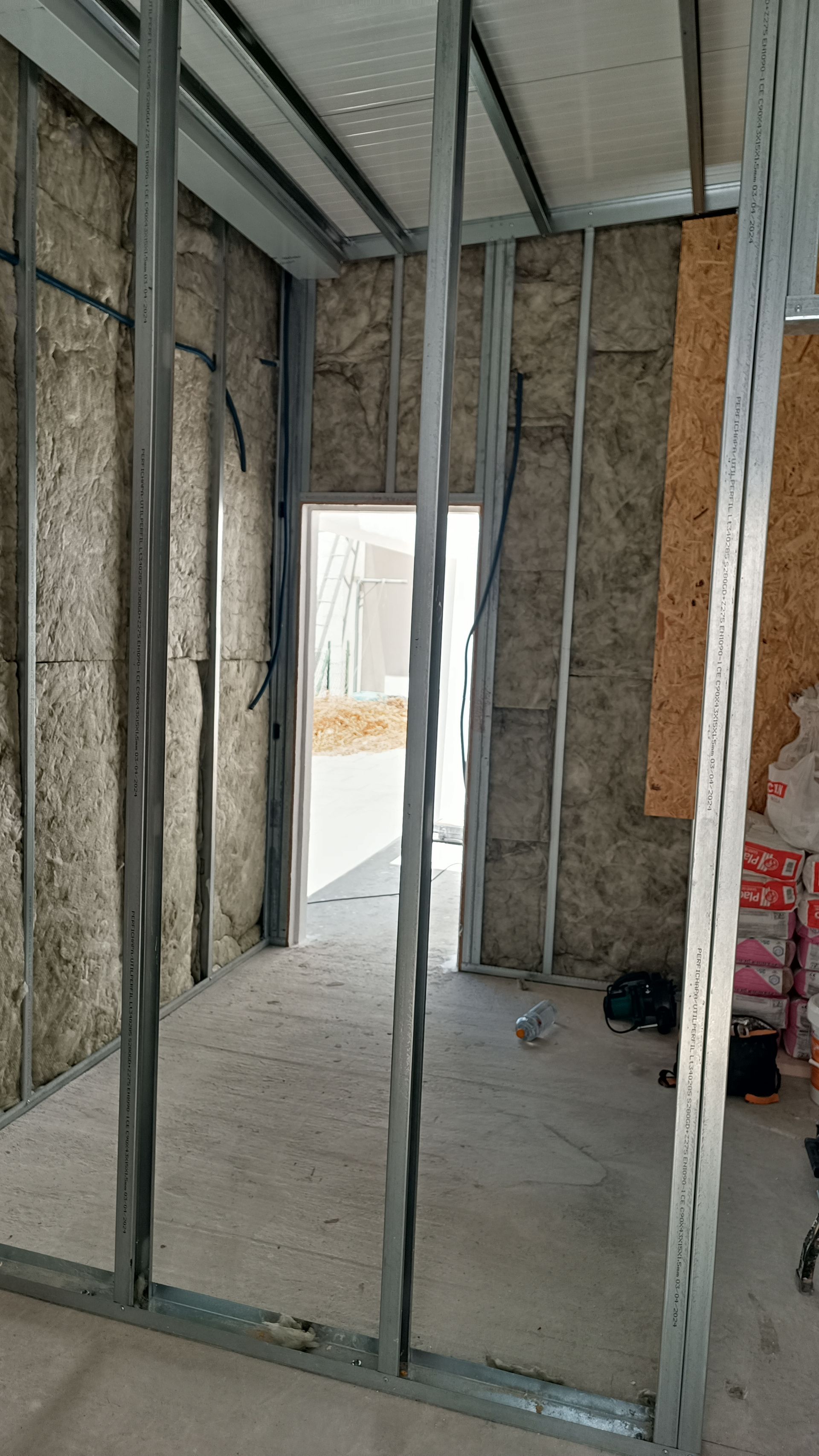 Construção interna, estrutura metálica para as paredes, isolamento aparente, porta de entrada, inacabada.