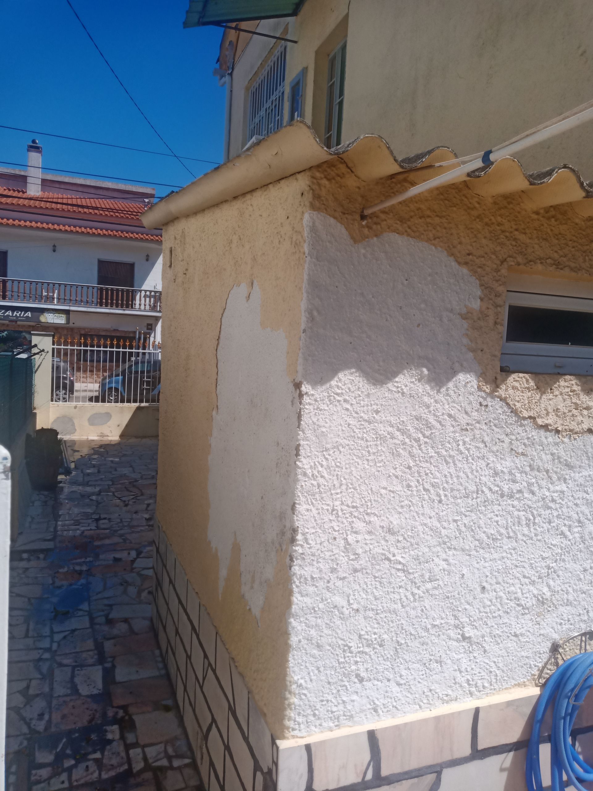 Prédio com estuque texturizado, em tons de bege e branco, ao lado de um céu azul.