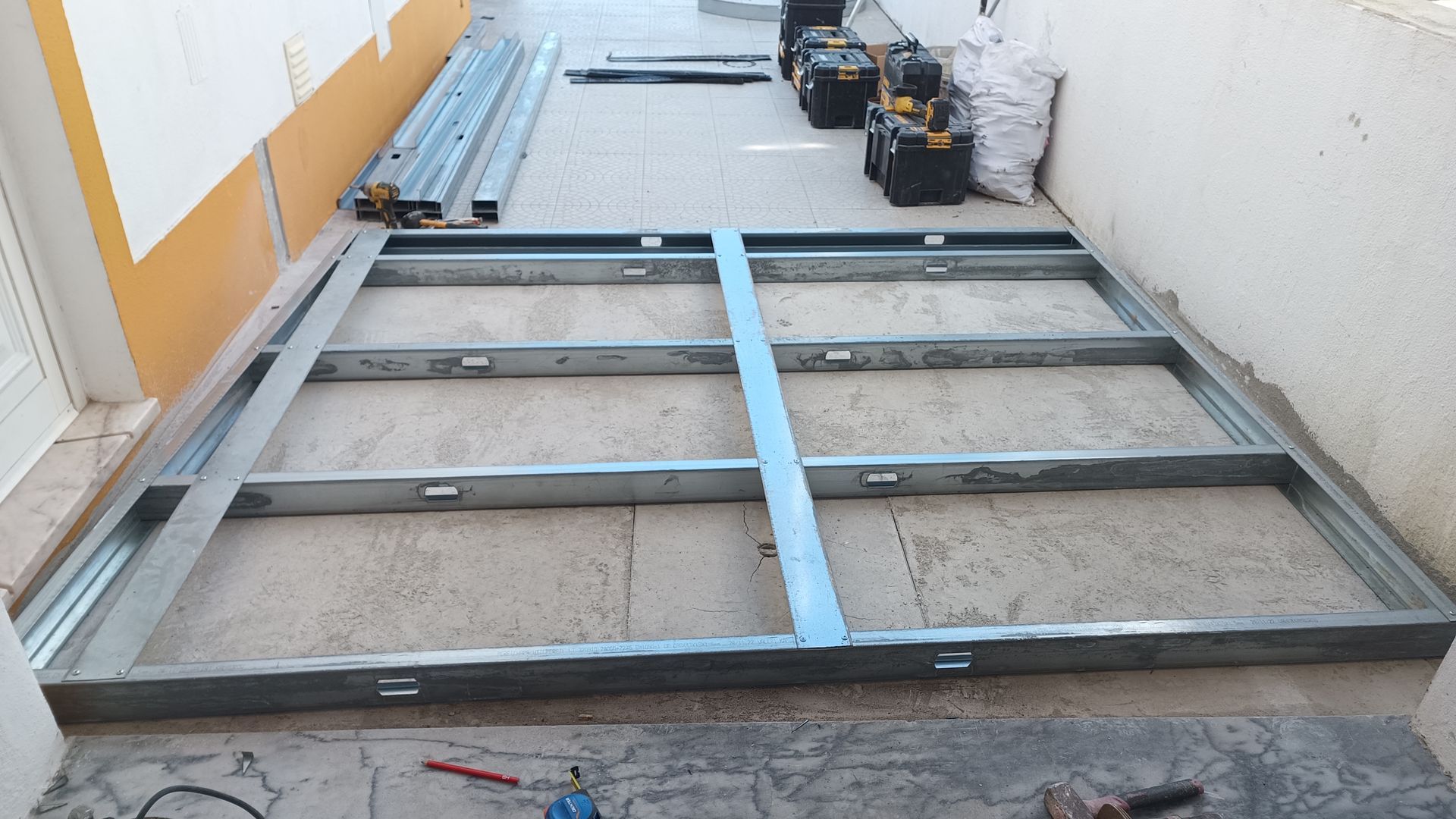 Estrutura metálica montada sobre uma superfície de concreto, com ferramentas e materiais por perto.