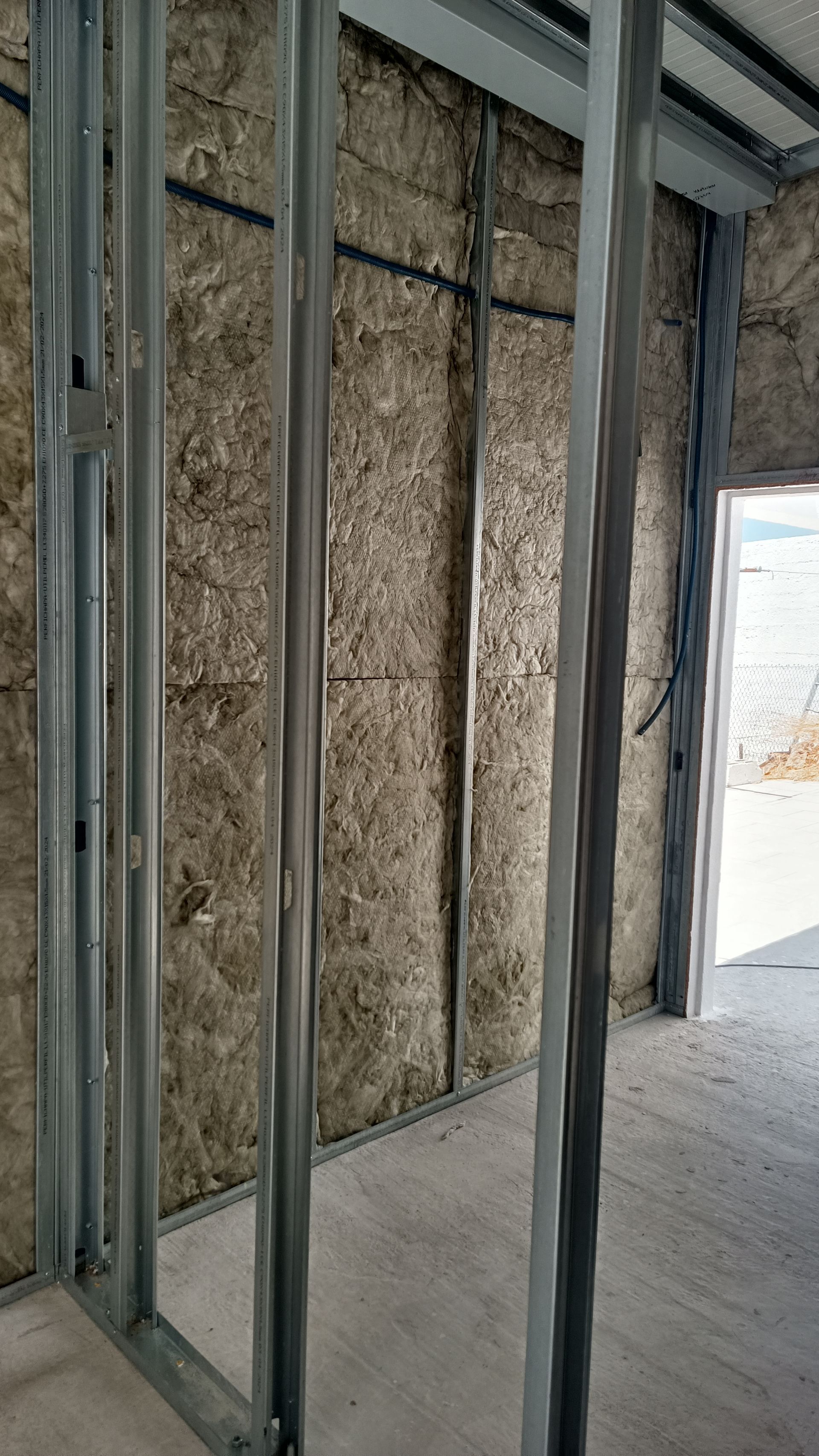 Estrutura metálica interna com isolamento visível; porta ao fundo.