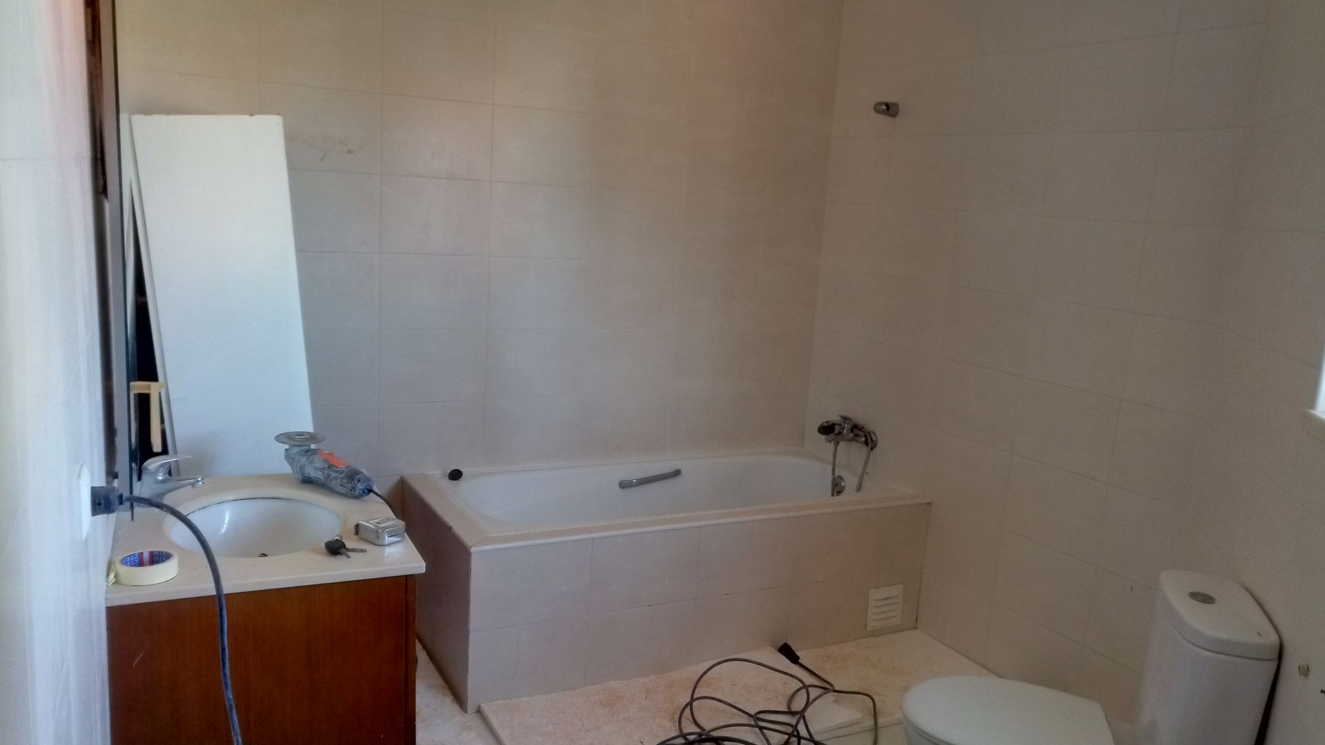 Banheiro em reforma; inclui banheira, vaso sanitário, pia e fiação exposta.