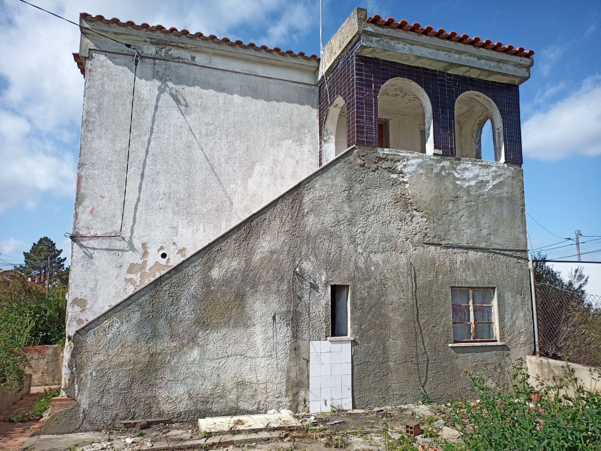 Prédio de dois andares com escadaria. A parte superior possui arcos e o exterior está desgastado pelo tempo.