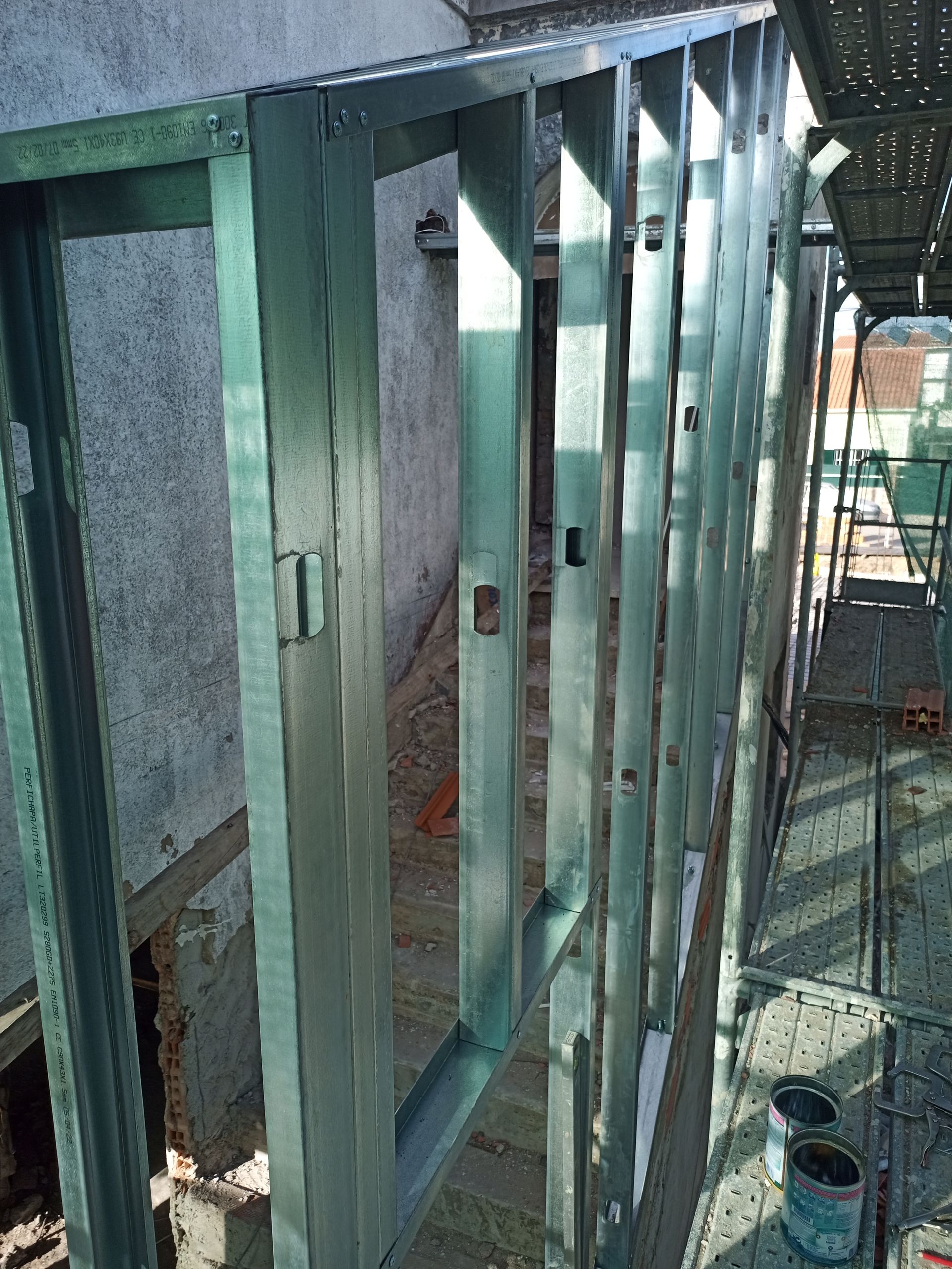 Estrutura metálica para parede com abertura para porta, em área externa, com andaimes.