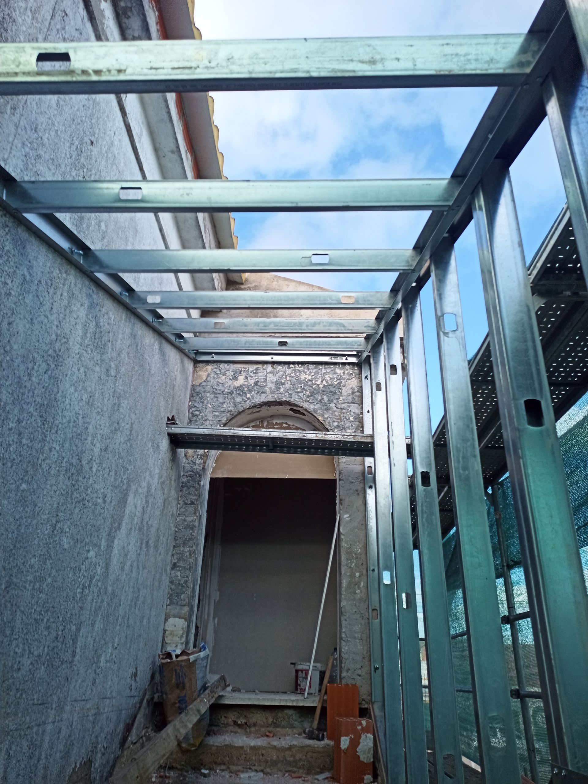 Estrutura metálica de uma porta, com céu azul visível.