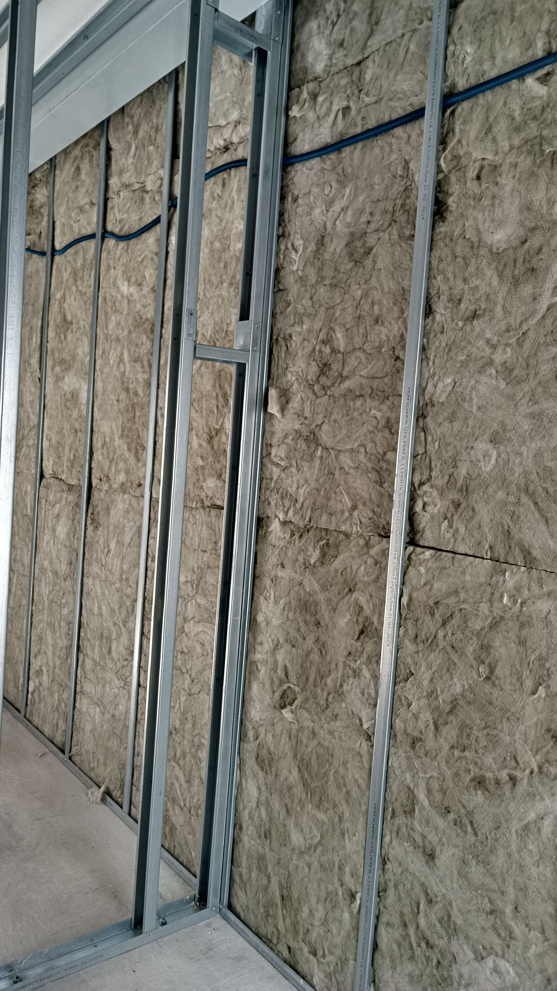 Estrutura metálica de parede com isolamento instalado, pronta para receber drywall.